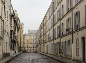 Quiet cobblestone street lined with neutral-toned buildings and soft shadows