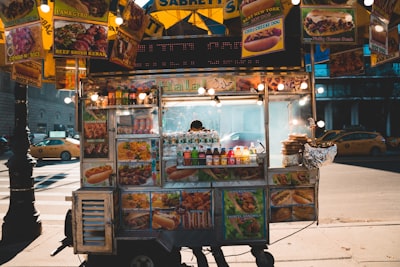 person standing behind food cart during nighttime honest teams background