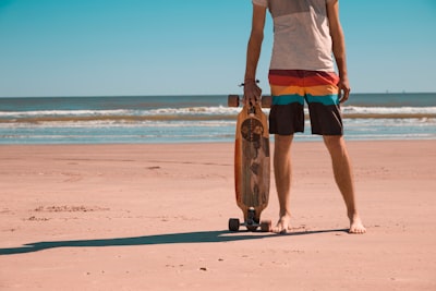 man holding longboard standing at sea shore texas zoom background