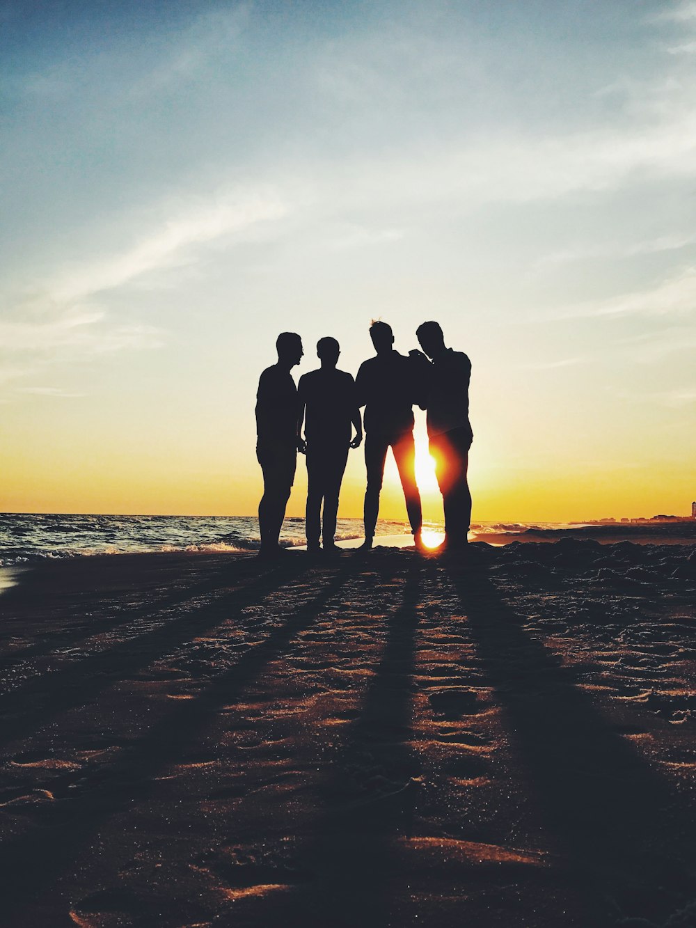 photographie de silhouette de quatre personnes debout sur le rivage