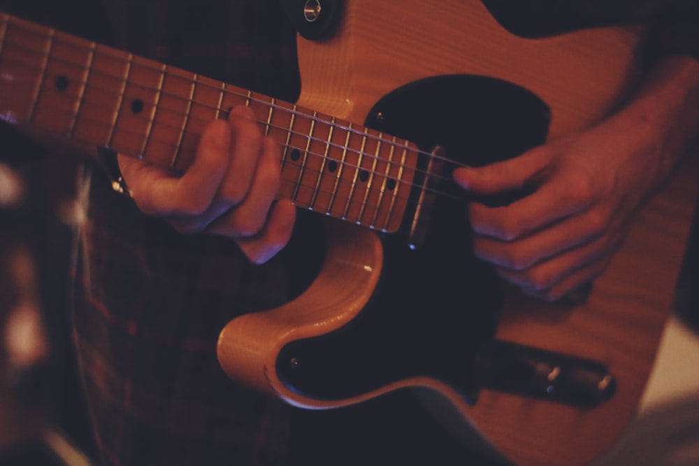 person playing brown and black guitar