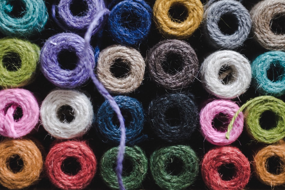 A grid of colorful yarn balls in many shades viewed from above, a crafter's yarn stash