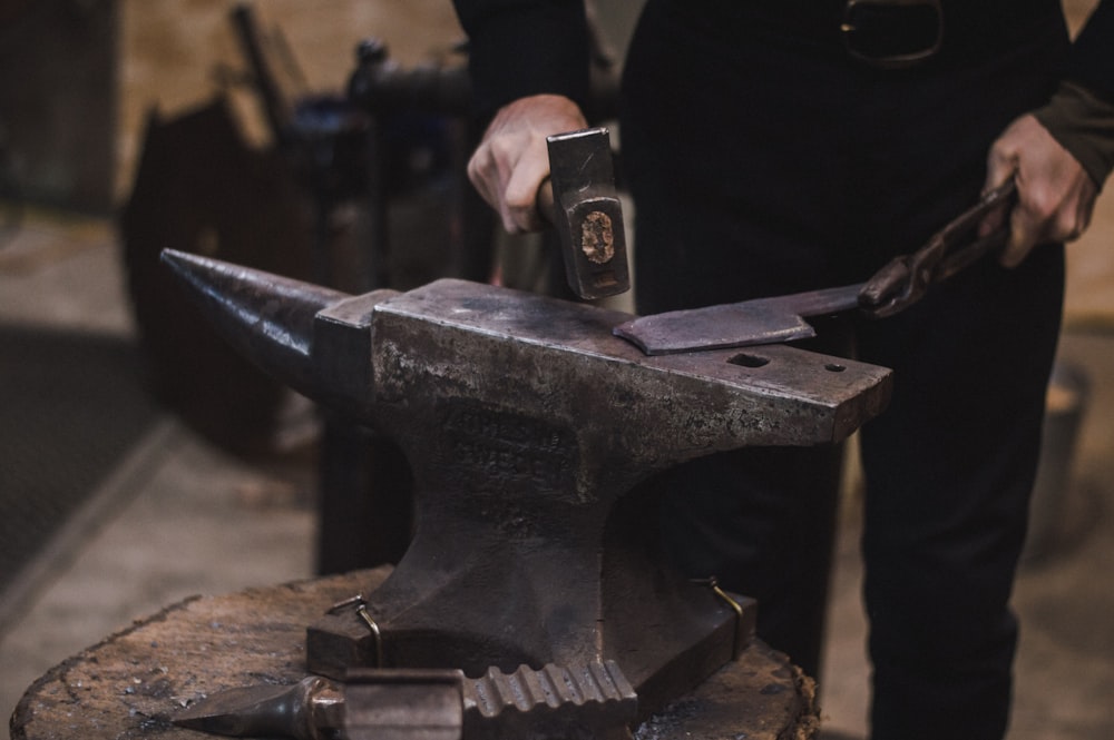 person hammering metal using hammer