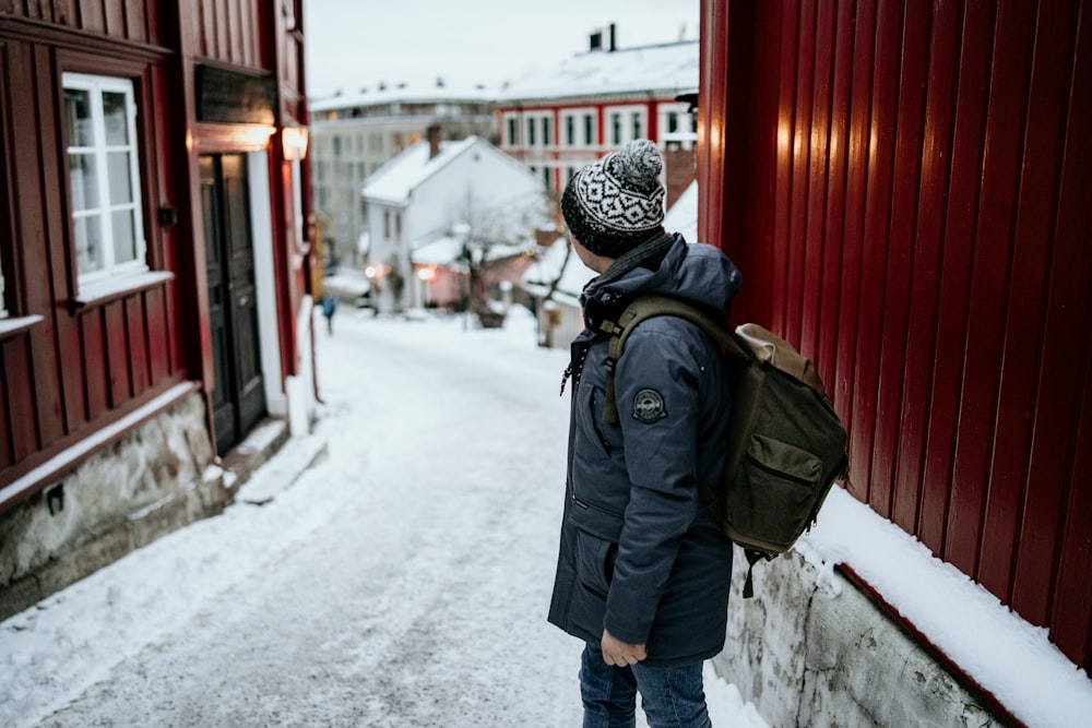 person carrying backpack standing between houses