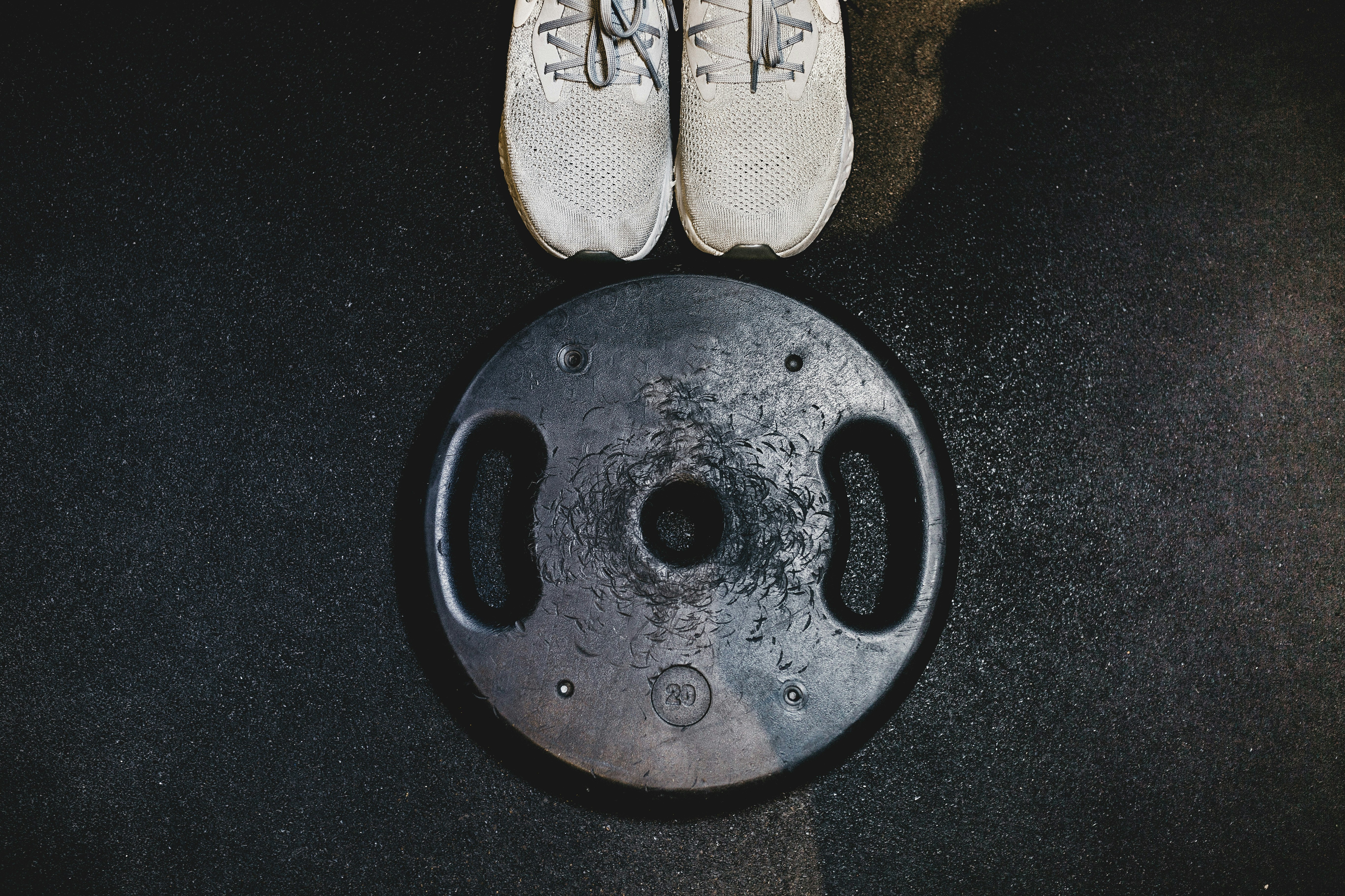 black weight plate beside white sneakers