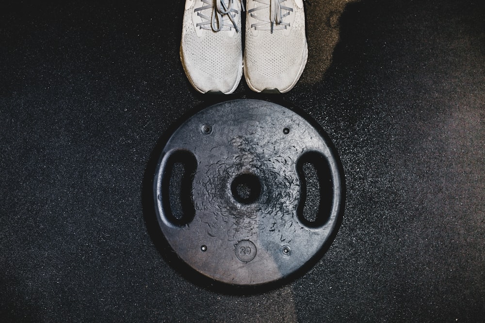 black weight plate beside white sneakers