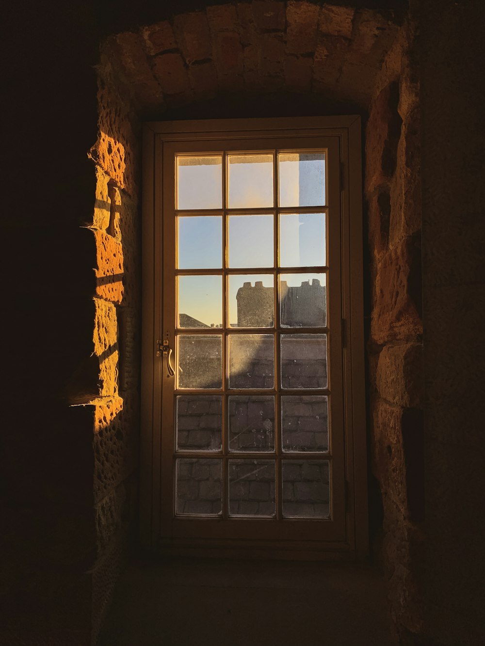 closed white framed glass window facing concrete bricks