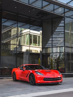 Sporty red coupe showcased against a minimalist modern building backdrop highlighting its aerodynamic curves