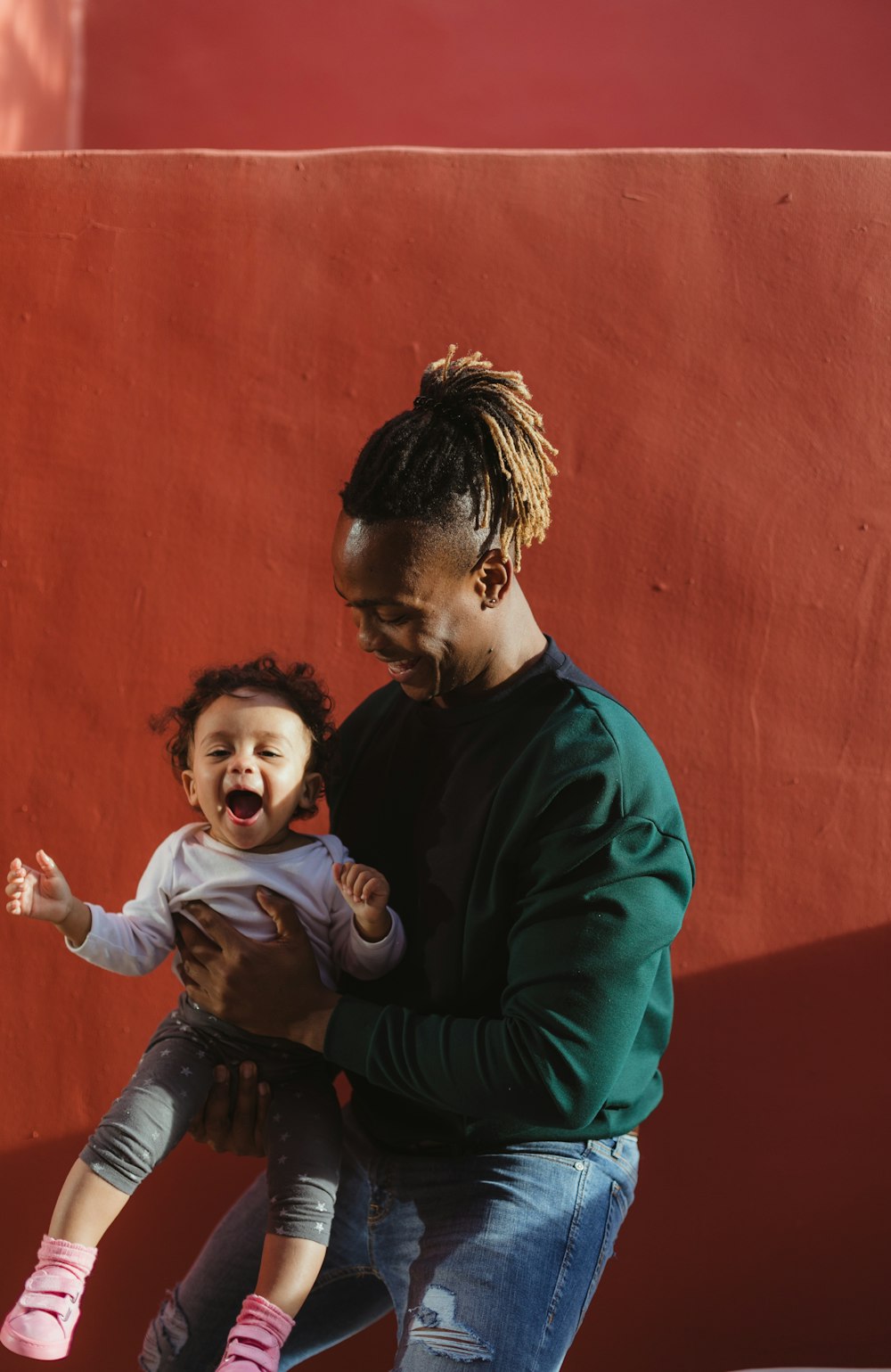 smiling man carrying child and playing