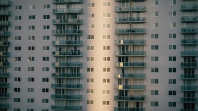 A high-rise residential building with a modern design featuring multiple floors and numerous windows. The structure is characterized by protruding balconies aligned in stacks, providing an urban and geometric aesthetic.