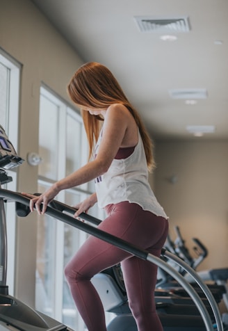 woman wearing white tank top exercising on gym equipment