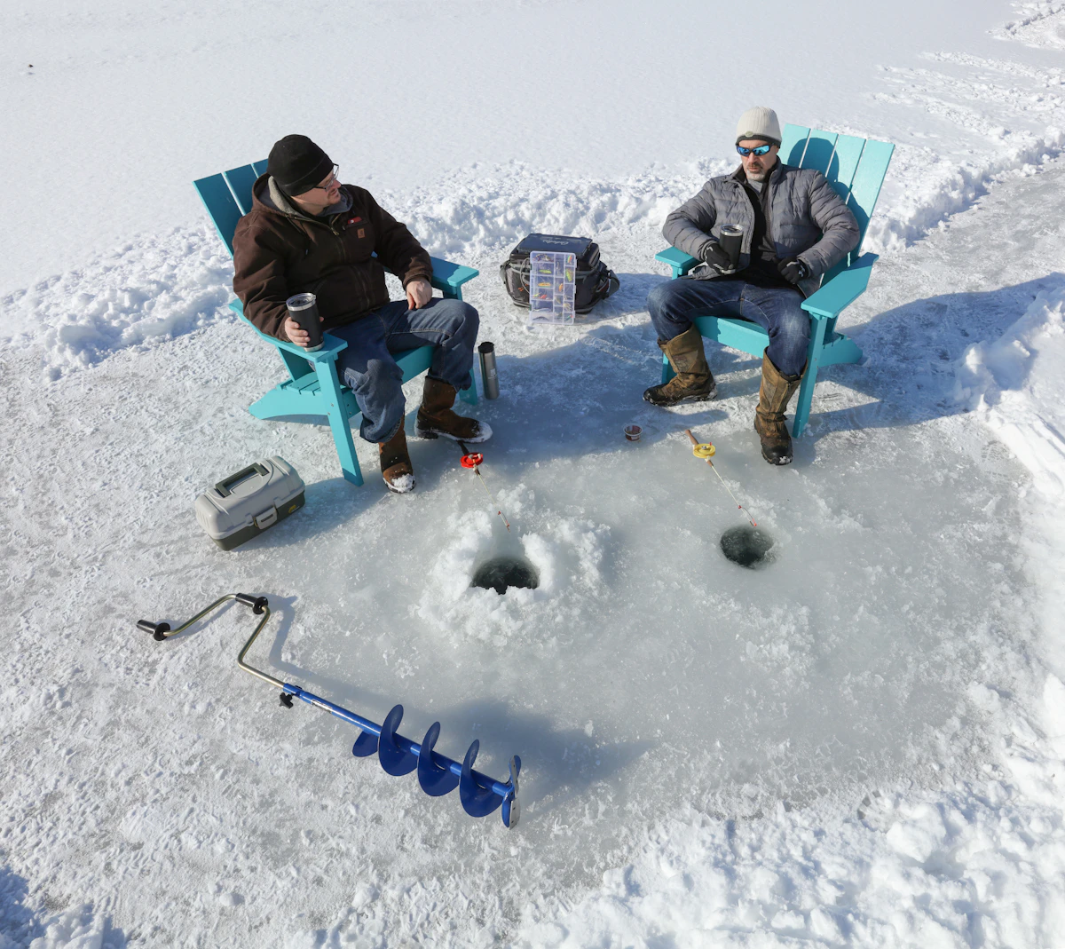Ice fishing gear beside a hole drilled through a frozen lake