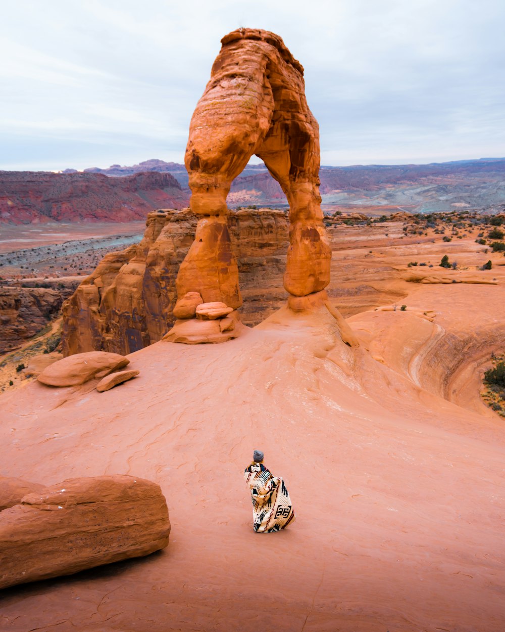 aerial view photography of woman standing near rock formation during daytime