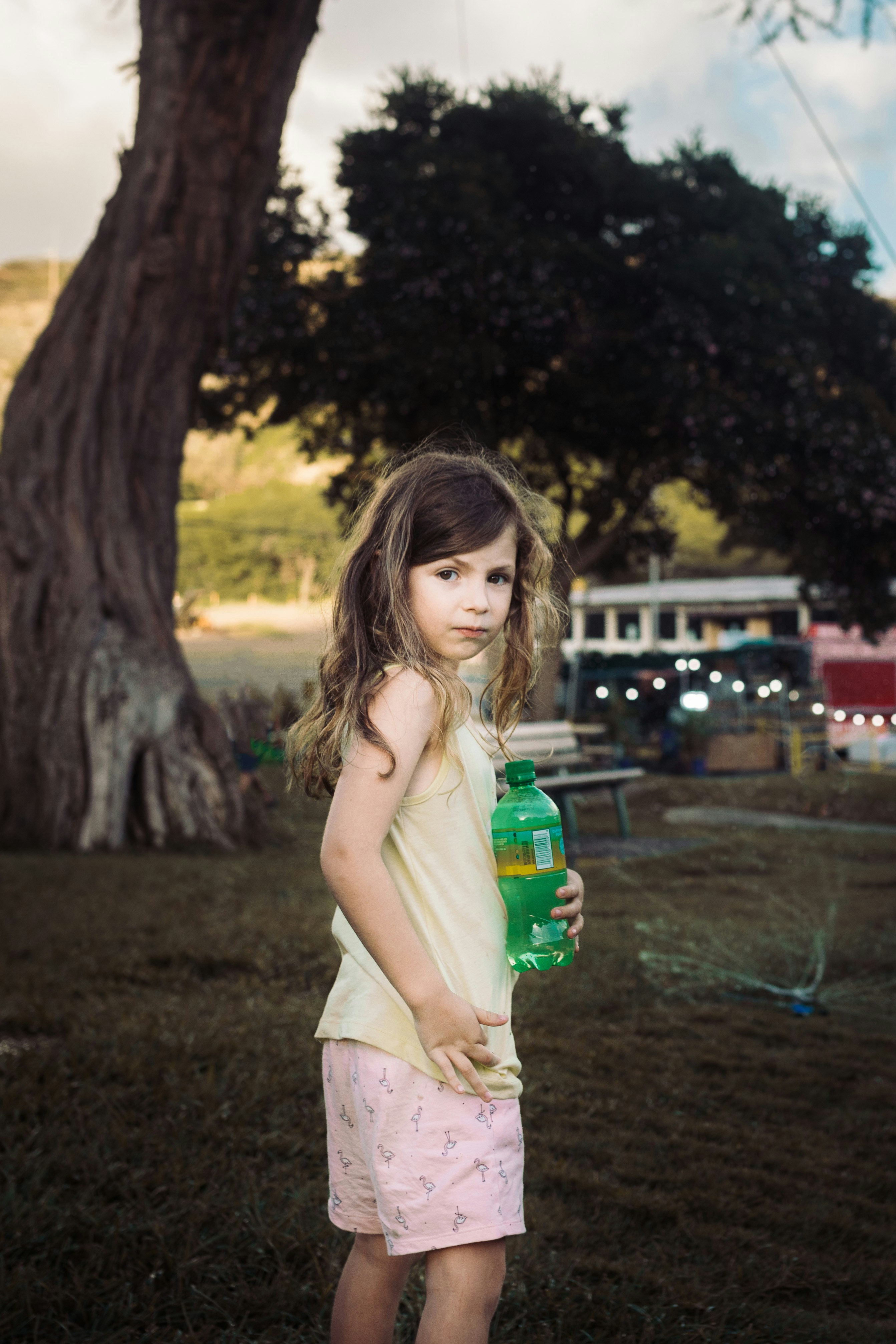 Girl Standing And Holding Bottle In Brown Field