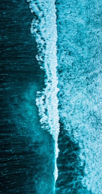 Vibrant coastline waves crashing, seen from above by a drone.