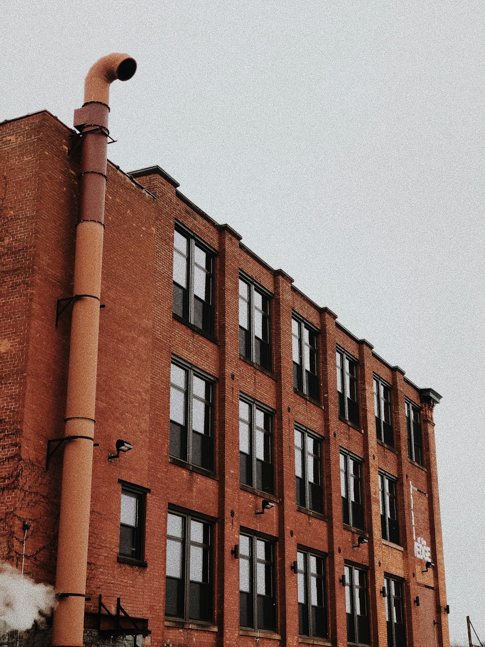 昼間は灰色の排気管がある赤いコンクリートの建物