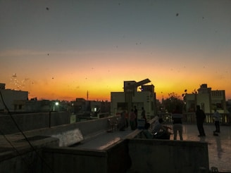 A vibrant city skyline at sunset with people gathered on a rooftop, sharing music and laughter.