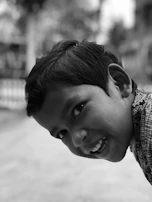 A black and white photo of a child laughing, caught mid-motion in a sunlit alley.
