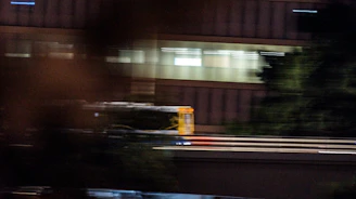 A sleek yellow and black bus gliding through a bustling city street at sunset.
