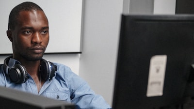 Customer support agent assisting a user with a headset in a professional blue-themed office.