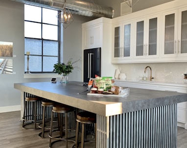 gray metal island table near white wooden kitchen cabinet