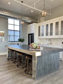gray metal island table near white wooden kitchen cabinet