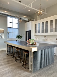 gray metal island table near white wooden kitchen cabinet