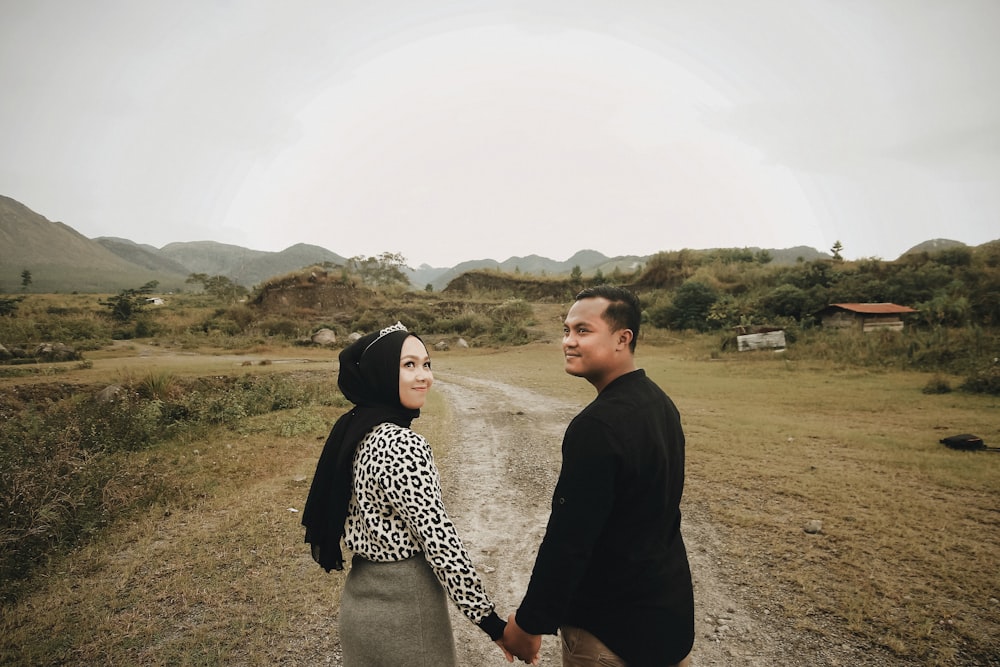 smiling woman and man holding hands while walking