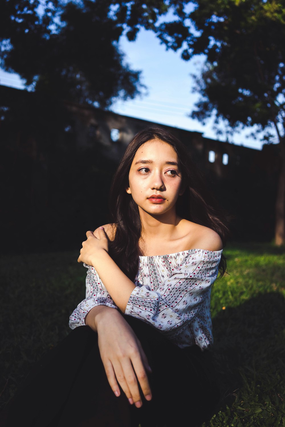 woman sitting on grass field under tree