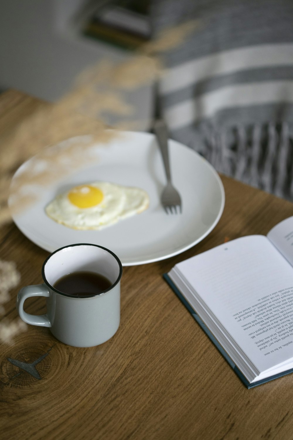 sunny side-up on plate beside a half filled mug