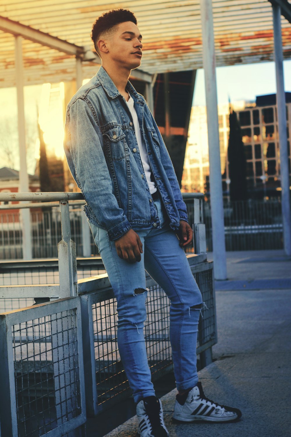 man in blue denim jacket leaning on safety hand rail
