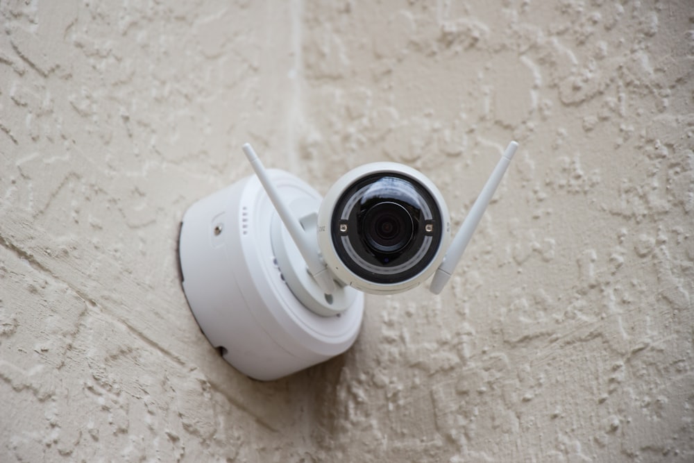 cámara de vigilancia blanca colgada en la pared