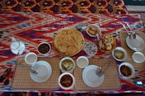 Bright dining table set with colorful tablecloth and neatly arranged dishes.