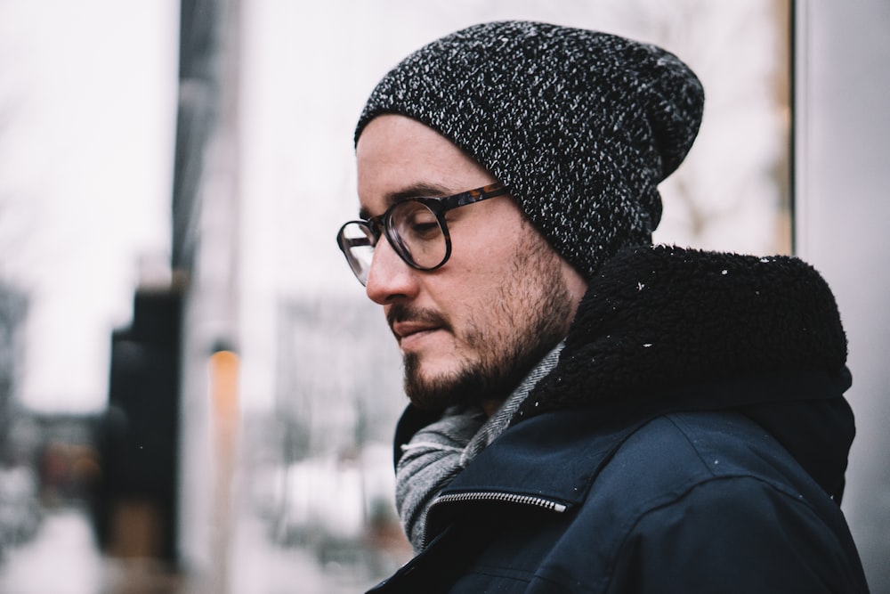 man looking down wearing coat and knit hat