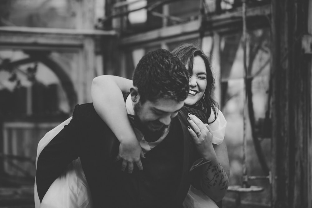 man and woman smiling while back hugging each other