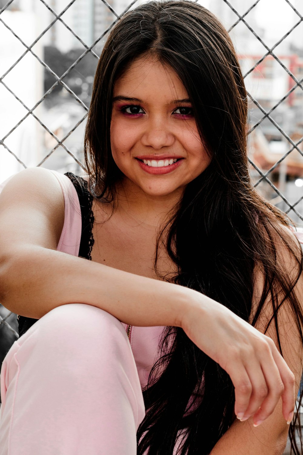 smiling woman sitting behind wire fence