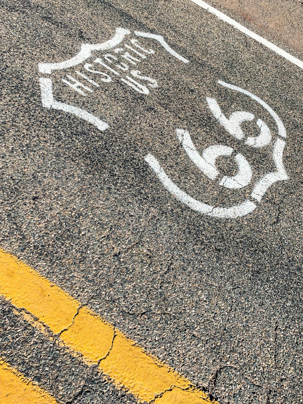 Historic US 66 sign on grey asphalt road during daytime