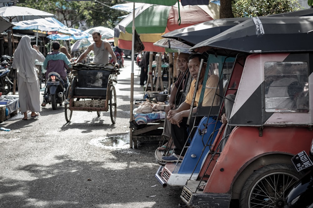 people sitting inside assorted-color passenger trikes during daytime