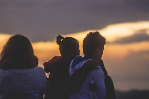 A diverse group of four happy people smiling together at sunrise.