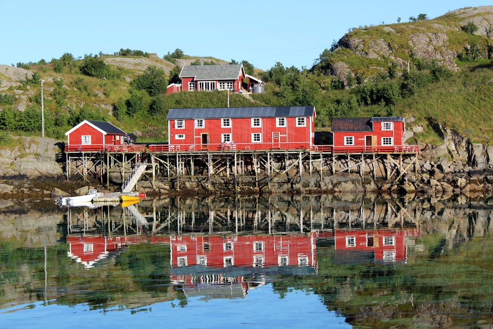 red wooden house beside body of water during daytime