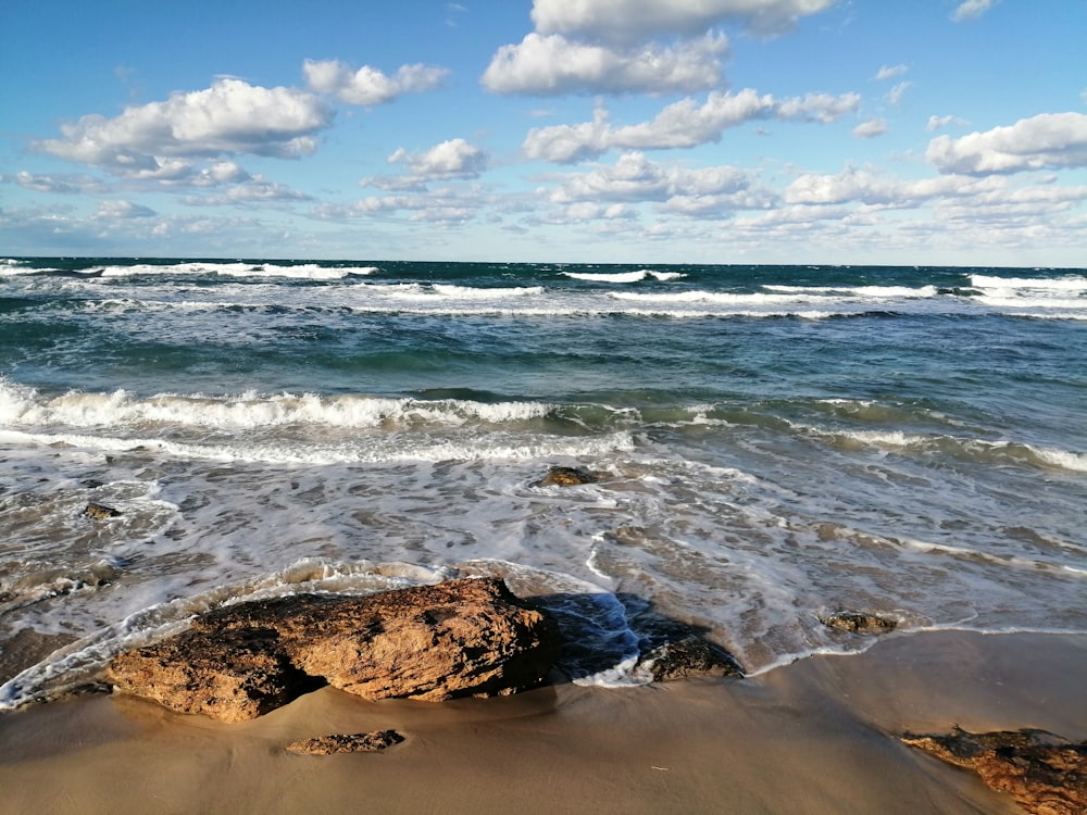 blue ocean waves under blue sunny cloudy sky during daytime