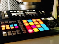A vibrant midi controller with colorful pads and keys illuminated during a music production session.