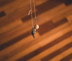A set of colorful 3D printed keychains hanging on a stylish wooden hook against a white wall