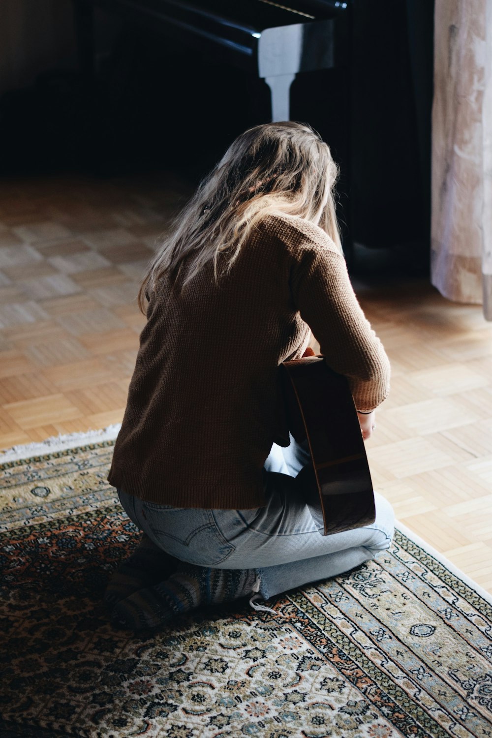 woman kneeling on rug while holding guitar