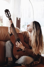 woman playing classical guitar near window inside room