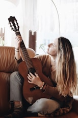 woman playing classical guitar near window inside room