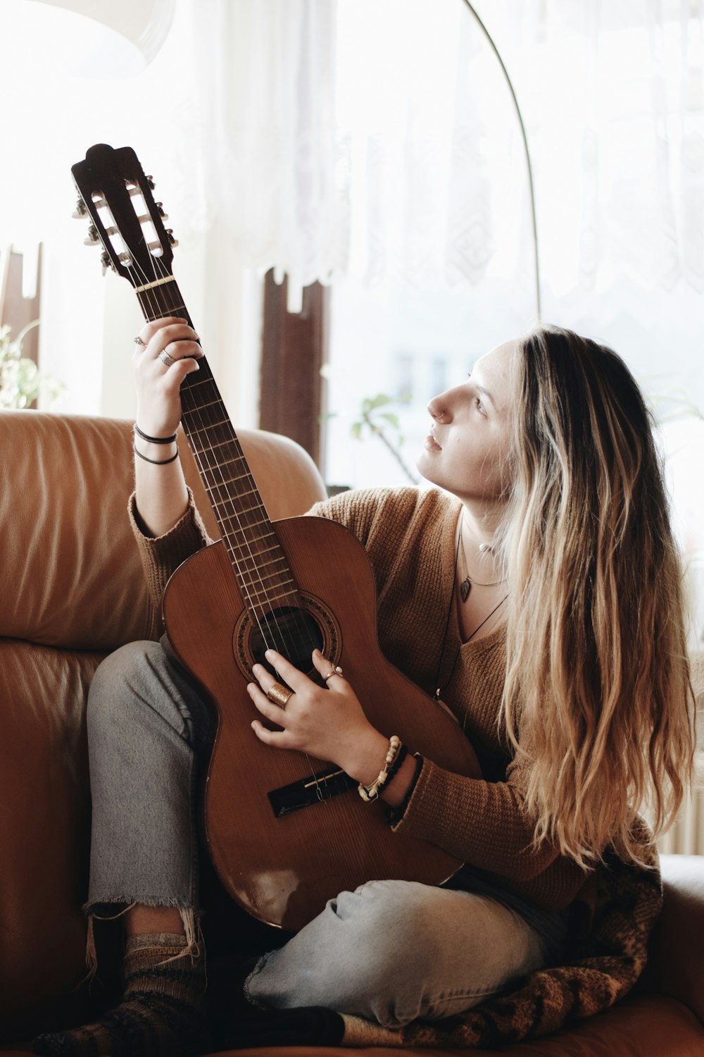 woman playing classical guitar near window inside room
