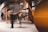 A modern interior setting featuring an abstract architectural design with curved and angular elements. The structure incorporates a mix of wooden textures and smooth surfaces, and there is a sense of motion blurred human figures passing through.