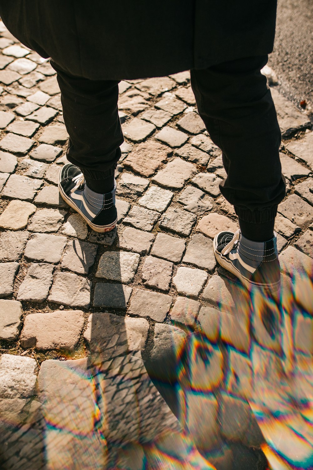 man in black pants wearing grey Pony high top skate shoes