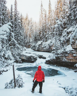 person in blue hoodie standing on ground covered by snow during daytime